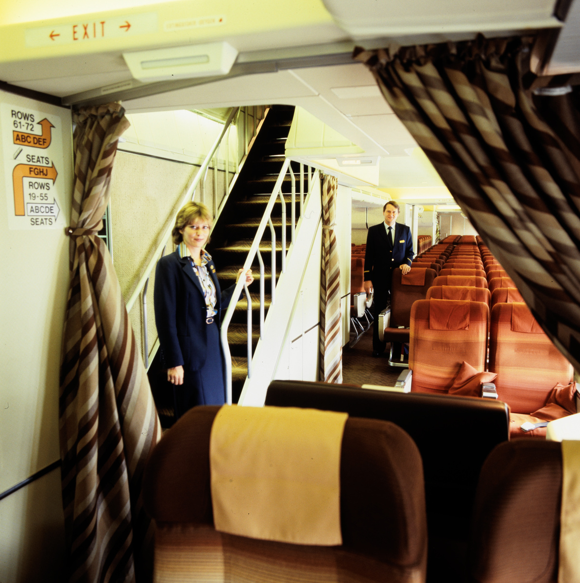 Hostess in der First-Class-Kabine vor dem Aufgang zum Upper Deck einer Boeing 747-300 der Swissair